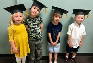 Four young students wearing graduation caps